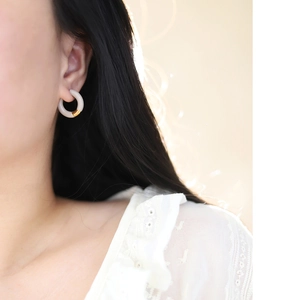 Detail of French enamel hoop earring in cream and 18K gold plating on a model