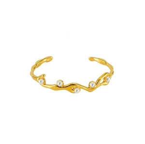Macro view of gold wavy bangle with five elegant white pearls in a minimalist design