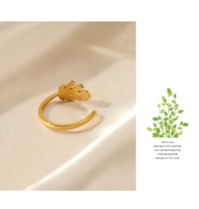 Close-up of gold leaf-shaped adjustable ring with brushed metal texture on silk fabric