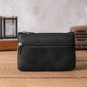Gros plan d'un porte-monnaie en cuir noir vintage avec double fermeture éclair sur bois rustique