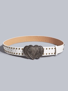 Detail of white studded belt featuring a vintage silver double heart embossed metal buckle