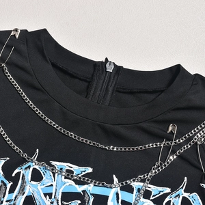 Gros plan d'un body streetwear noir avec chaînes en métal, épingles et fermeture éclair au dos