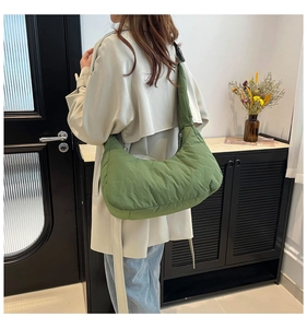 Detail of green quilted puffer crescent bag with soft padded strap and nylon texture