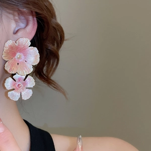 Detail of pink gradient flower earrings with pearls worn by a model on clean background