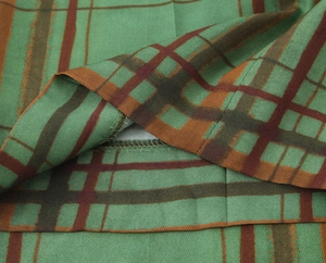 Detailed close-up of dark green plaid twill fabric with precision stitching and soft drape