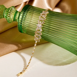 Detail of luxury gold plated bracelet with cubic zirconia on green glass and silk