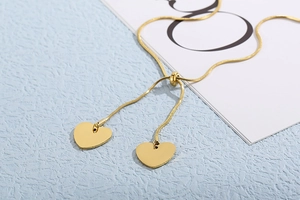 Detail of adjustable gold snake chain necklace with dual polished heart pendants