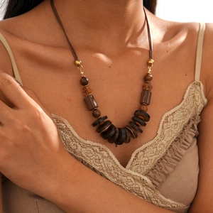 Detail of bohemian necklace featuring dark brown wood beads and natural coconut shell accents