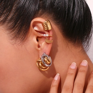 Close-up of stacked gold ear cuffs and twisted gold and silver hoop earrings on model