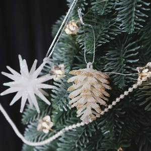 Champagne glitter pinecone and star ornaments hanging on a festive Christmas tree