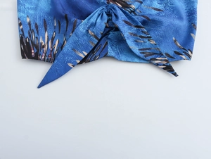 Detailed close-up of blue floral fabric knot with black and brown botanical patterns