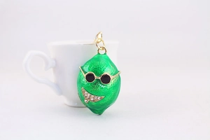 Macro di un portachiavi a limone verde con occhiali da sole e sorriso di strass