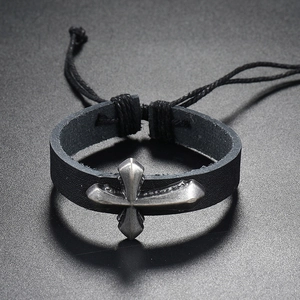 Detailed macro view of black leather bracelet featuring a vintage silver cross and adjustable cord