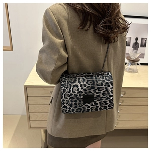 Lifestyle shot of a stylish leopard print crossbody bag with a metal chain strap