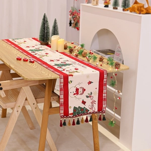 Detailed view of red and beige Christmas table runner with snowman and tassel accents