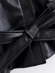 Close-up of black faux leather jacket showing belt tie detail and premium grain texture