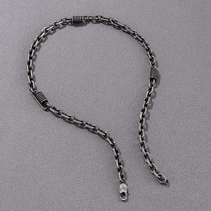 Detail view of vintage lobster clasp and spiral coil links on a steel chain necklace