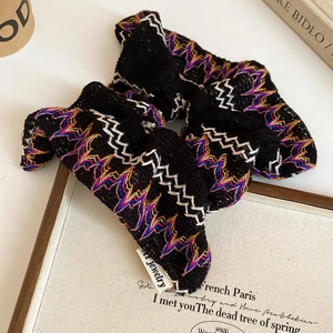 Vue détaillée d'un chouchou en maille noire avec broderie vagues colorées et étiquette