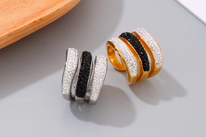 Detailed view of three-row geometric rings in gold and silver with black and white crystals