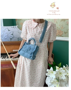 Detail of light blue washed denim crossbody bag featuring external pocket and wide strap