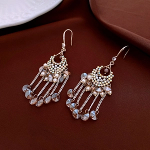 Detail of vintage gold flower crystal earrings with dangling tassels and shiny rhinestones