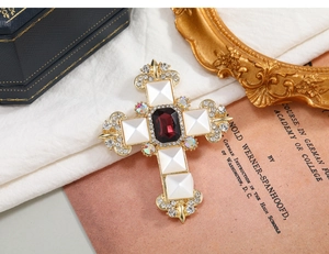 Macro detail of a vintage Byzantine style cross brooch with red and white gemstones