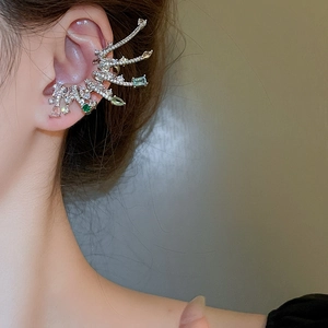 Gros plan sur un protège-oreille en zircon avec pierres vertes et motif branche