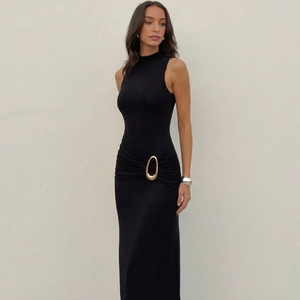 Gros plan sur la boucle en métal doré et les détails plissés à la taille d'une robe noire