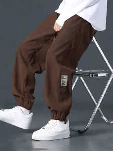 Detail of dark coffee corduroy joggers featuring side patch and premium ribbed texture