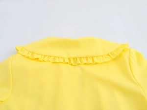 Macro shot of yellow blouse back neckline featuring ruffled edge and linen texture