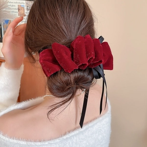 Détail d'un nœud papillon en velours bordeaux avec rubans noirs sur un chignon