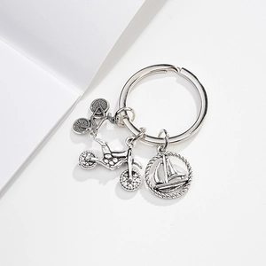 Close-up of silver metal keychain featuring bicycle, motorcycle, and sailboat charms