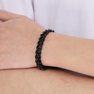 Close-up of a matte black stainless steel Cuban link bracelet worn on a male wrist