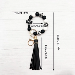 Detail of silicone bead keychain with cross pendant, black tassel, and size dimensions