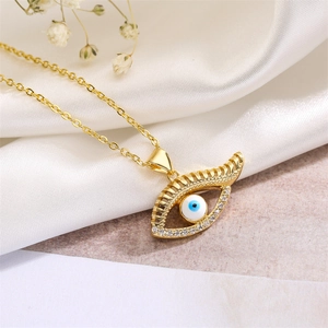 Detailed macro view of gold Evil Eye pendant with colorful crystals on white silk