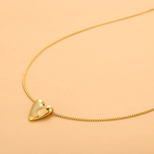 Detailed view of a polished gold heart pendant on a delicate stainless steel chain