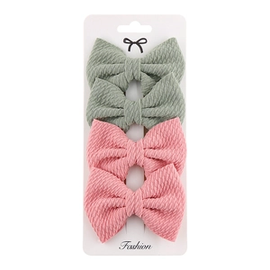 Detailed view of four polyester bow hair clips in pink and sage green on a display card