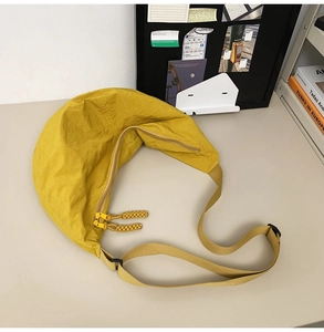 Détail du sac croissant en nylon jaune avec bandoulière réglable sur un bureau
