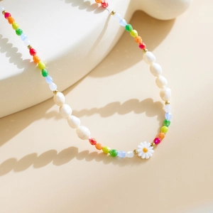 Detail of bohemian necklace with colorful faceted beads, pearls, and a white daisy charm