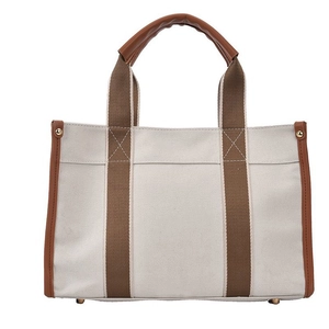 Minimalist canvas tote bag with brown leather handles and contrast trim on white background