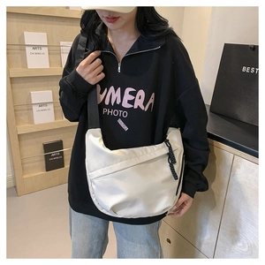 Detail of white nylon crossbody bag featuring black woven zipper cord and minimalist style