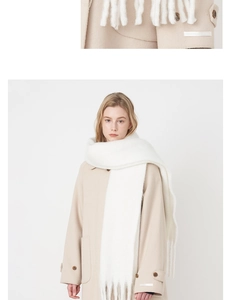 Close-up of soft white cashmere-like scarf with fringe detail and beige wool coat