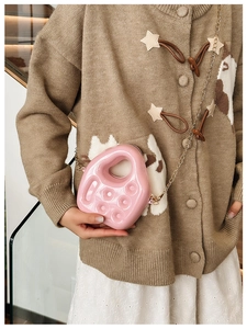 Detail of pink PVC jelly bag with gold metal chain strap worn by a female model