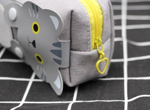 Detail of grey canvas pencil case featuring heart zipper pull and cute cat patch
