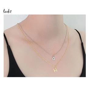 Close-up of layered gold and silver letter pendants D and H with sparkling zircon stones