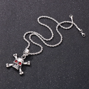 Detailed macro shot of silver skull pendant with red gemstone eyes on a black textured surface