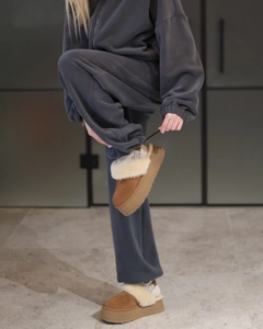 Detail of dark grey fleece tracksuit paired with platform sheepskin boots in brown