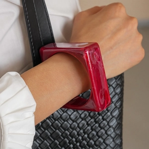 Red square acrylic bangle with ink swirl texture shown on model with white shirt