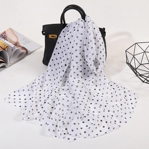Classic black and white polka dot chiffon scarf draped on a handbag for women