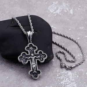 Silver Orthodox cross pendant with twisted rope chain resting on a smooth black stone